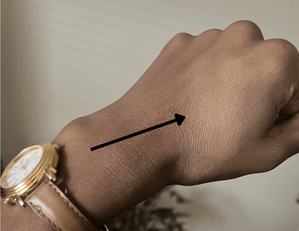 A swatch of Mac Mineralize Skinfinish in the shade Dark swatched on brown skin.